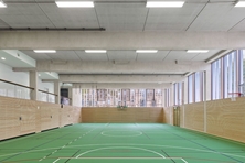 Kepler Sporthalle im EG mit grünem Boden und Holzvertäfelung an der Wand, im Hintergrund ist das Gerichtsgebäude sichtbar