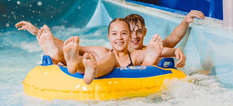 Ein Mädchen und ein Junge in einem gelben Rutschreifen im Donaubad