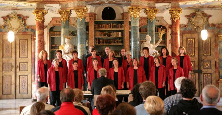 Ein rund 20-köpfiger Chor singt in einem prachtvollen Saal.