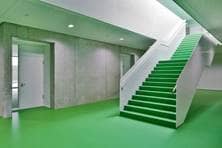 Innenbereich des Hochschulgebäudes mit grünem Boden, grüner Decke und einer Treppe mit grünen Stufen.