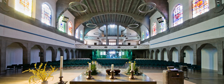 Innenraum mit einem Altar und bunten Kirchenfenstern